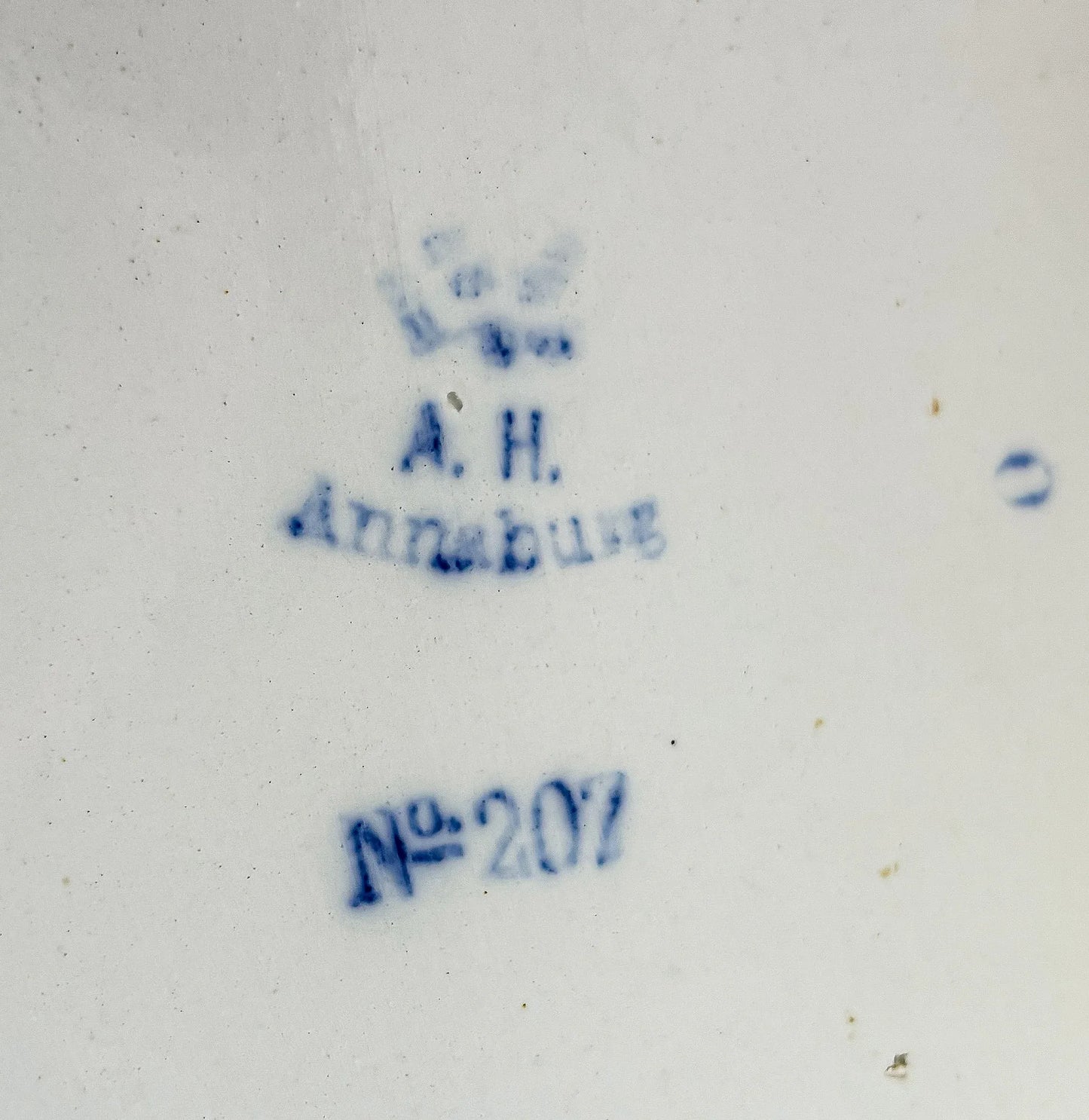 Extreme close-up of the blue underglaze backstamp on the antique German stoneware, showing the imperial crown and eagle crest, the text A.H. Annaburg, and production number No. 207.
