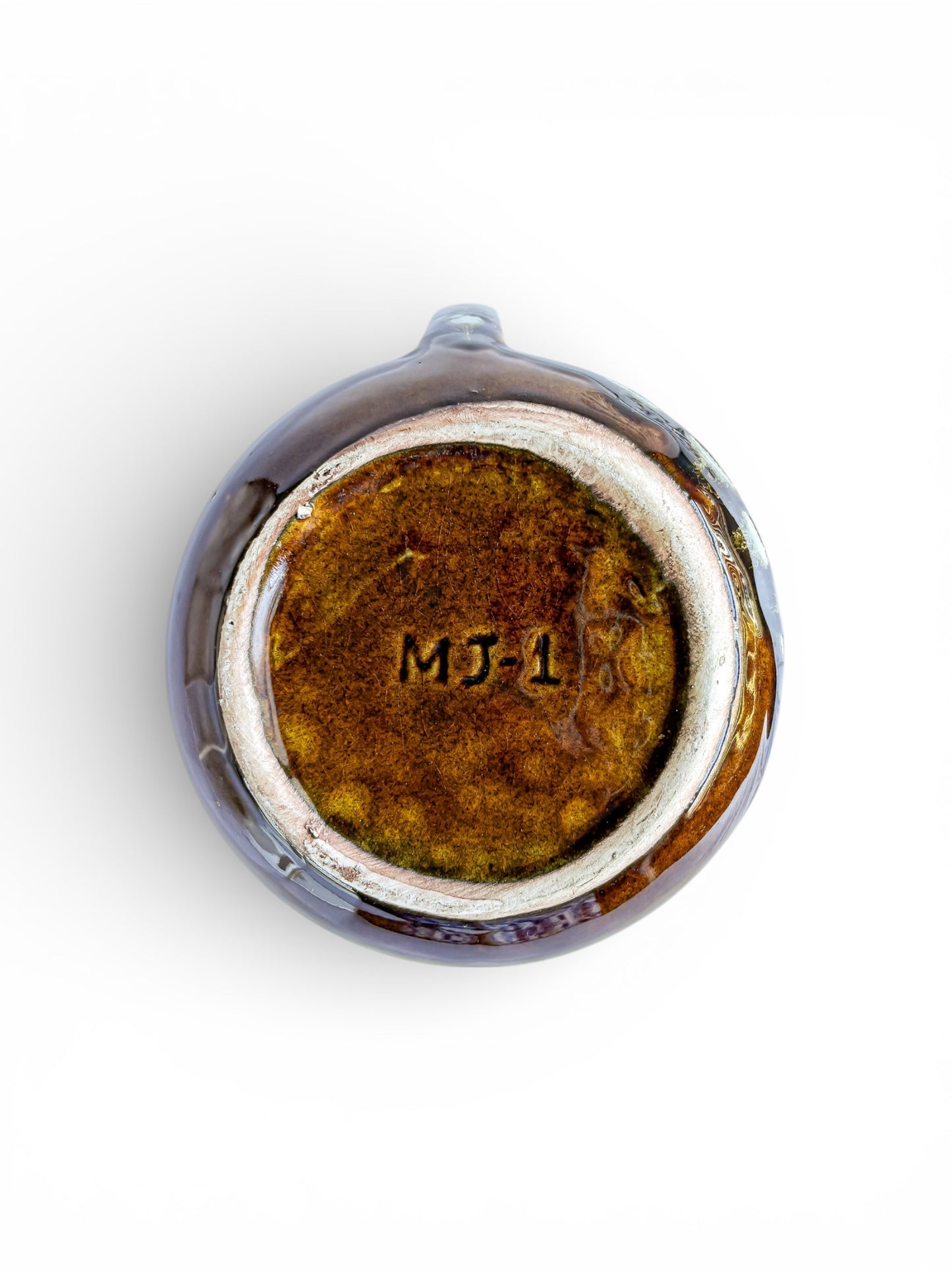 Bottom of a brown glazed ceramic teapot with handle, marked MJ-1, on white background