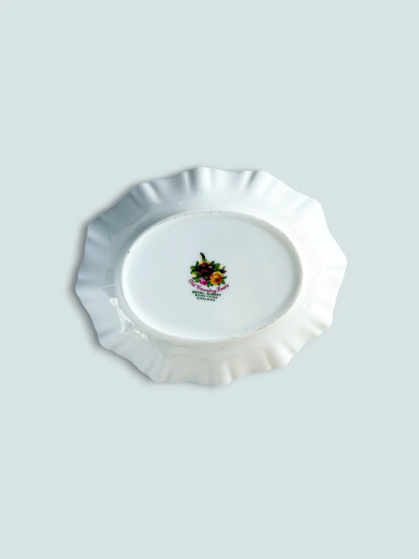 The underside of a Royal Albert Old Country Roses dish, displaying the official green and pink backstamp. The hallmark includes the pattern name and "Royal Albert Bone China England," confirming its authentic heritage and origin.
