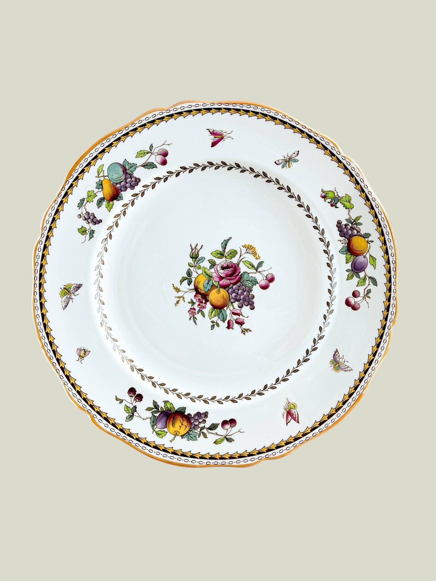 White ceramic plate with floral and fruit design, gold rim, and butterfly accents