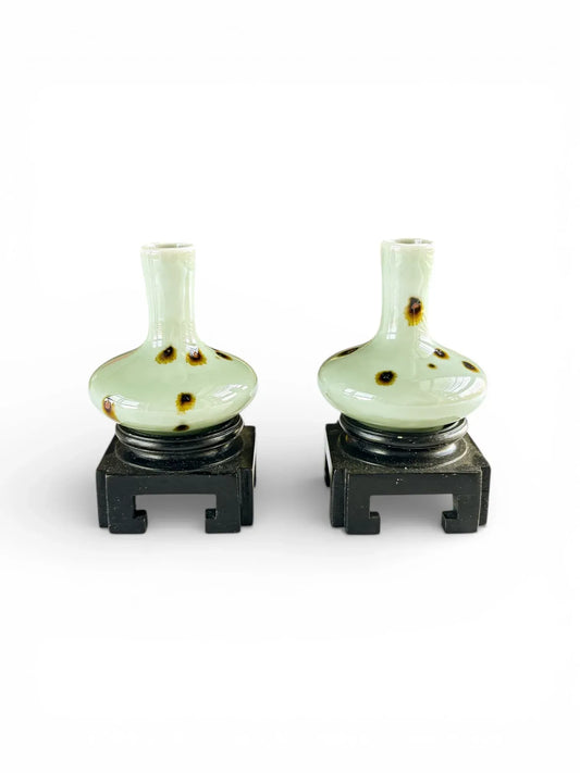 Matching pair of miniature Tobi Seiji spotted celadon vases on carved dark hardwood stands. Pale sea-green Kinuta glaze with iron-brown splashes.