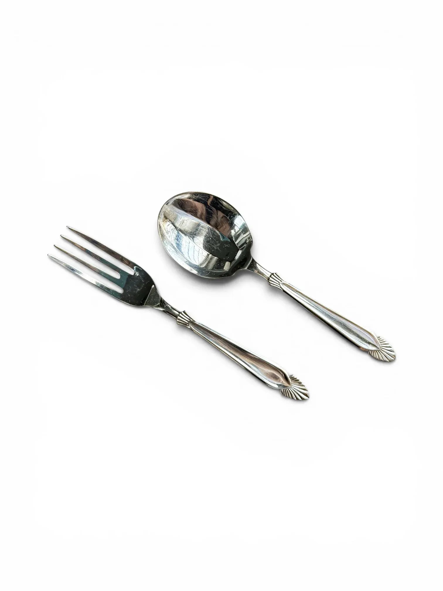 A matching pair of vintage silver-plated dessert fork and spoon by Angora, highlighting the polished mirror finish and Art Deco-inspired shell and fan motif on the handle finials.