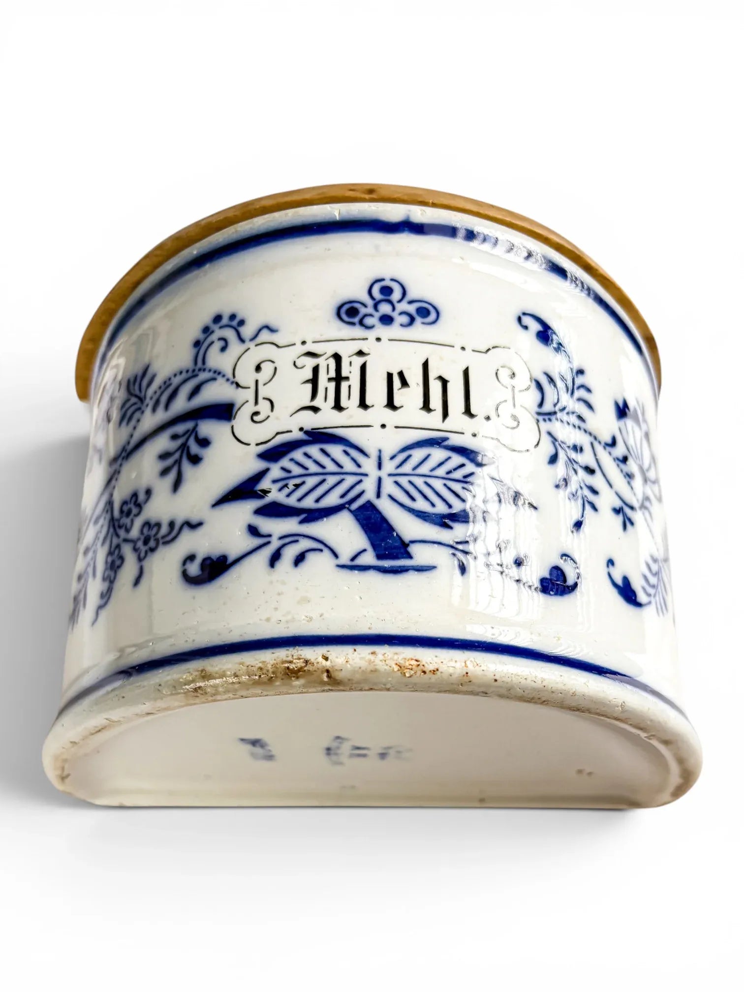 Low-angle front view of the antique German ceramic flour box, highlighting the Mehl Gothic lettering and the unglazed, rustic bottom rim against a white background.