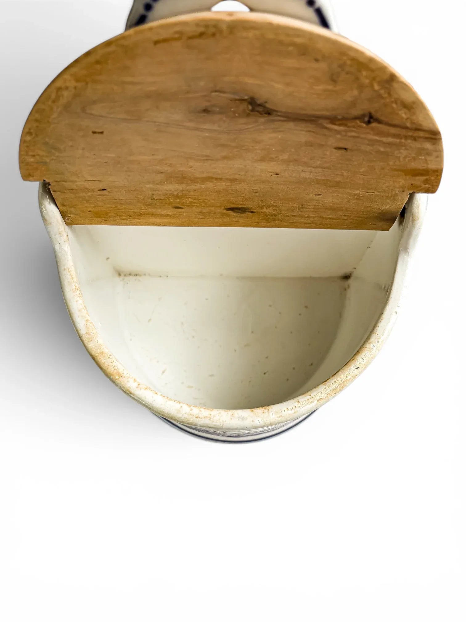Interior view looking down into the open, white glazed basin of the antique ceramic box, showing the underside of the open wooden lid and natural age-staining along the rim.
