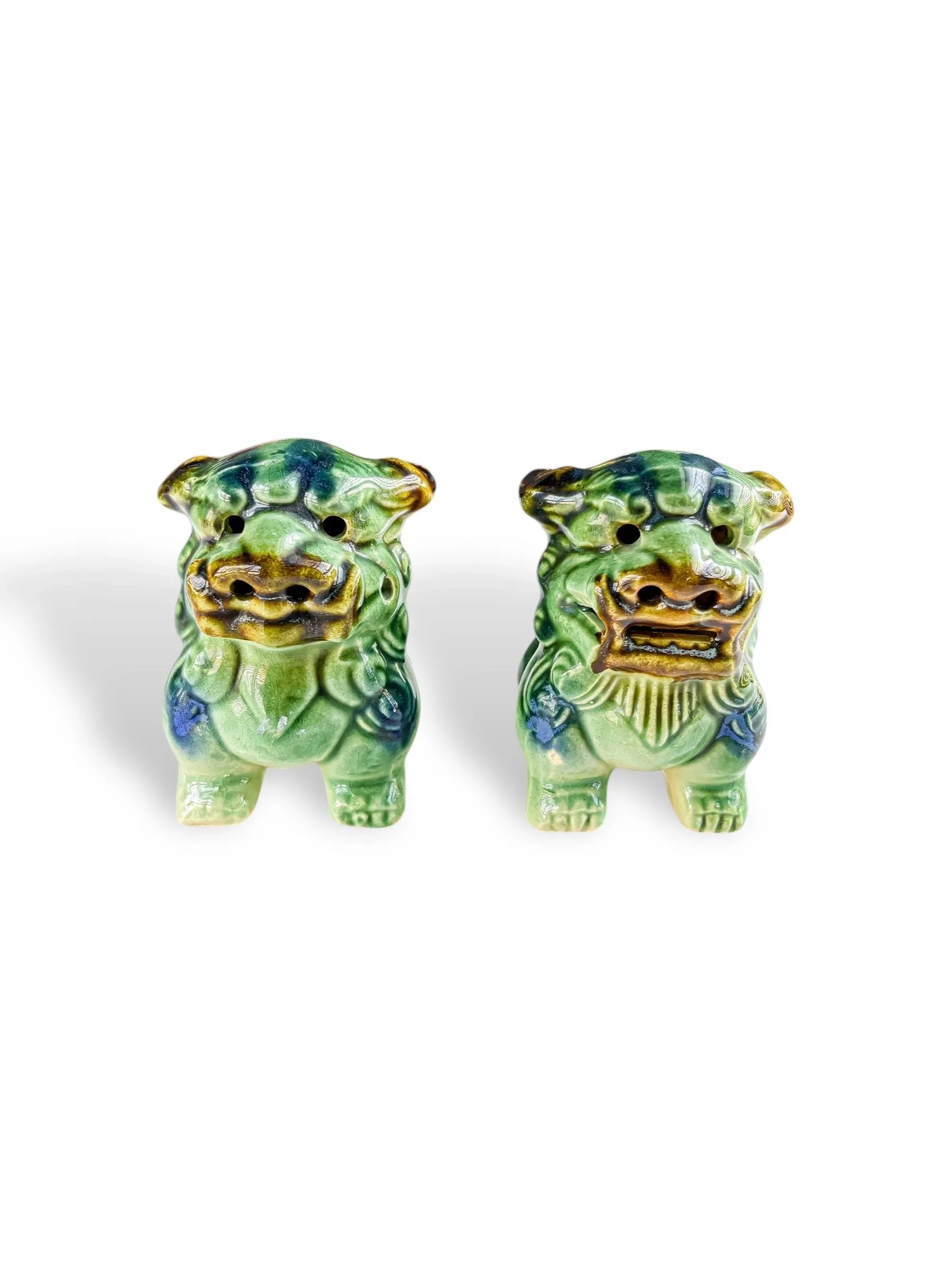 Pair of green ceramic Shisa lion dog statues with blue and brown accents on white background