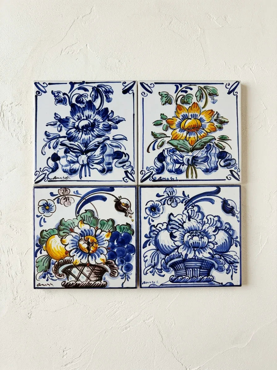 Set of four vintage hand-painted Azupal Portuguese tiles displayed on a textured plaster wall.