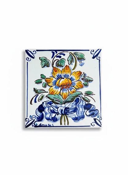 Detailed shot of a polychrome Azulejo tile with a yellow and blue flower bouquet and bow motif.