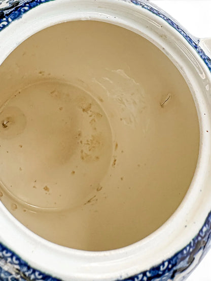 Interior of the teapot showing tea staining, brown spotting and a short vertical line on the right-hand wall at the handle join.