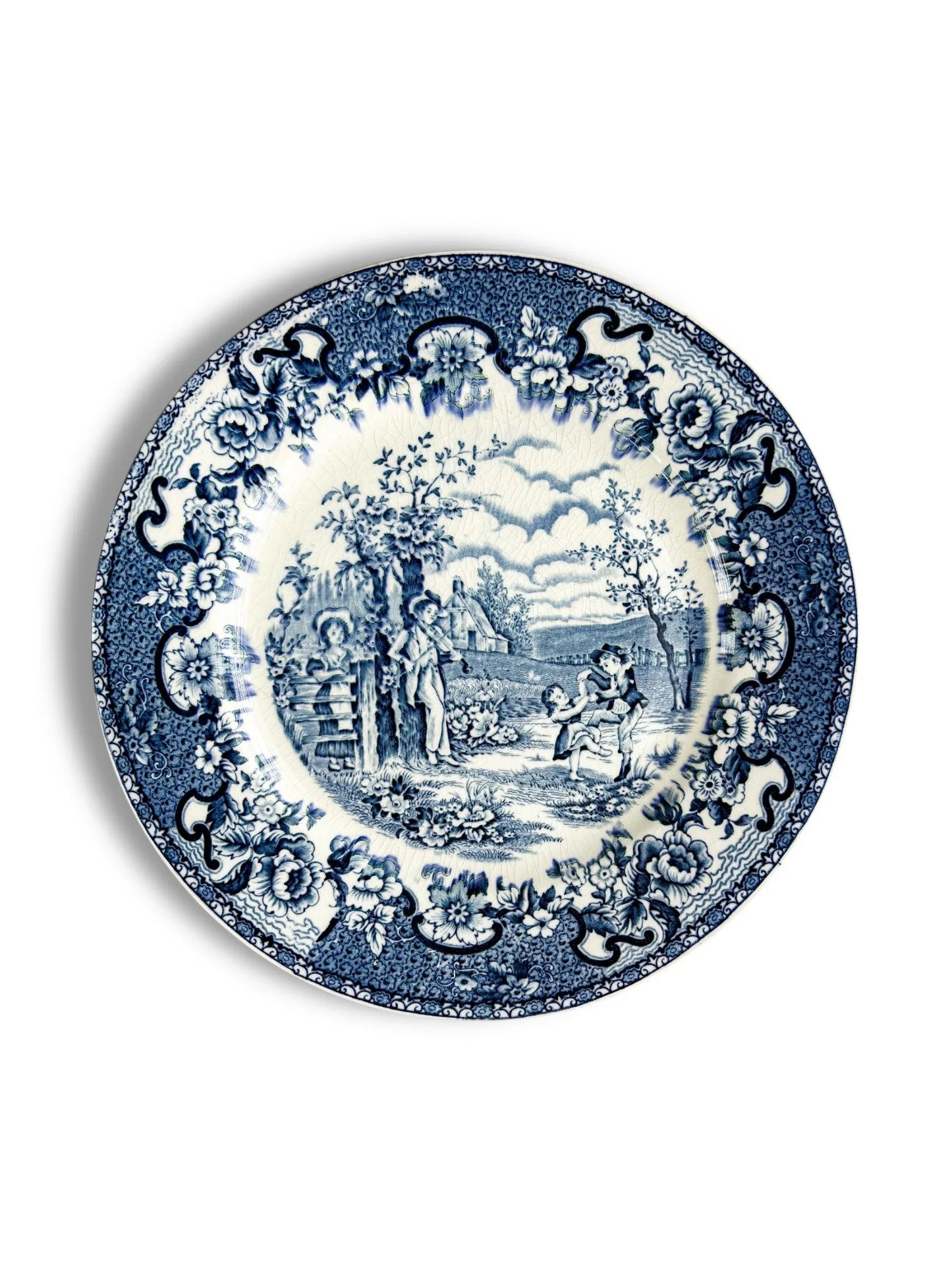 Blue and white vintage ceramic plate with floral border and countryside scene with children playing