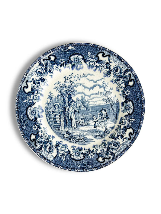 Blue and white vintage ceramic plate with floral border and countryside scene with children playing