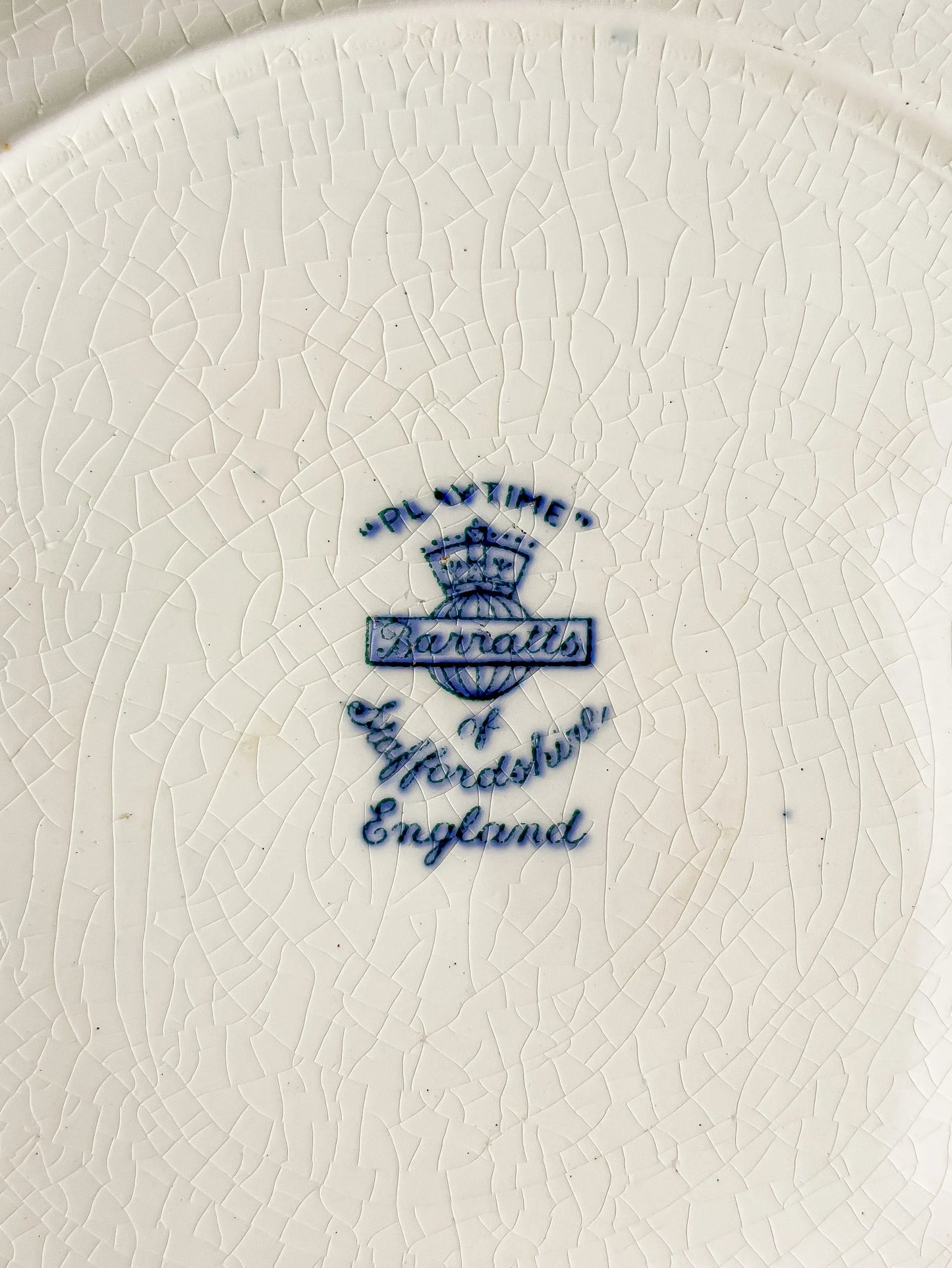 Close-up of vintage Barratts Staffordshire England mark on cracked white ceramic plate