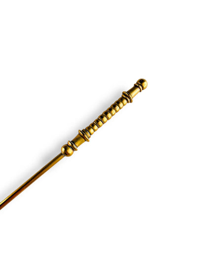 Gold-toned intricately carved metal wand with rounded decorative rings on white background