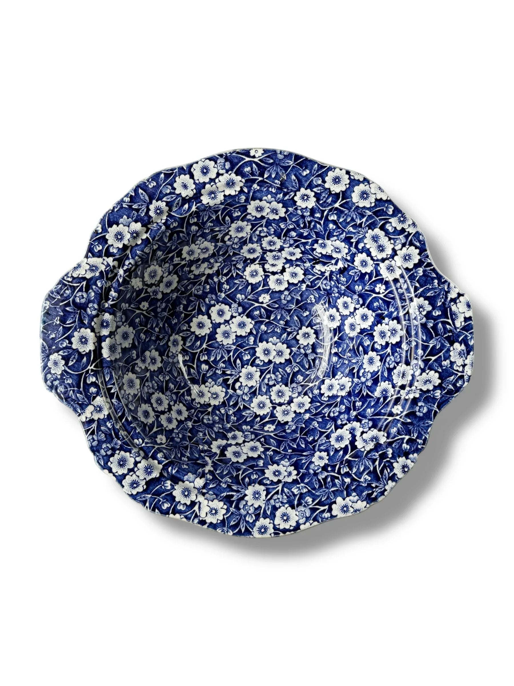 Blue and white ceramic bowl with intricate floral pattern and scalloped edges