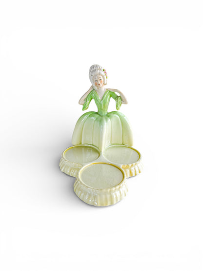 Vintage porcelain trinket dish in the shape of a woman wearing a green dress with three round compartments