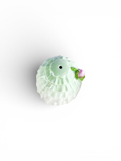 Top view of green and white porcelain vintage sugar bowl with pink flower accent on white background