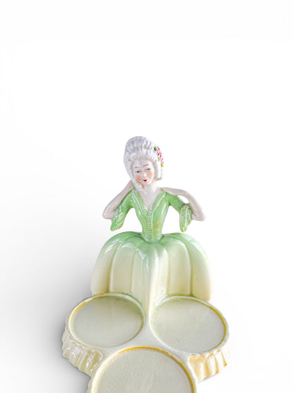 Vintage porcelain figurine of a woman in green dress with three round ceramic dishes, collectible tableware