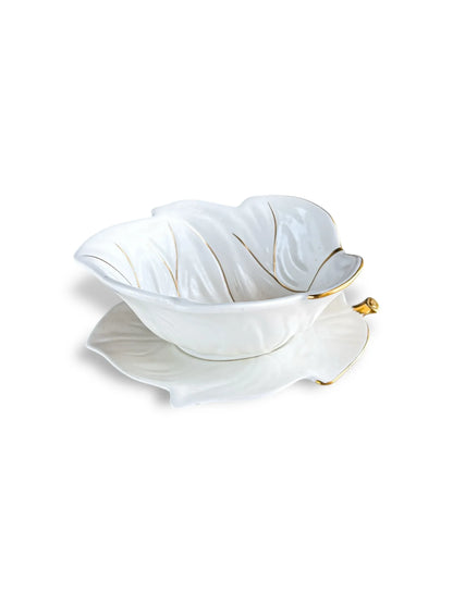 White ceramic leaf-shaped bowl with gold trim and matching plate on white background
