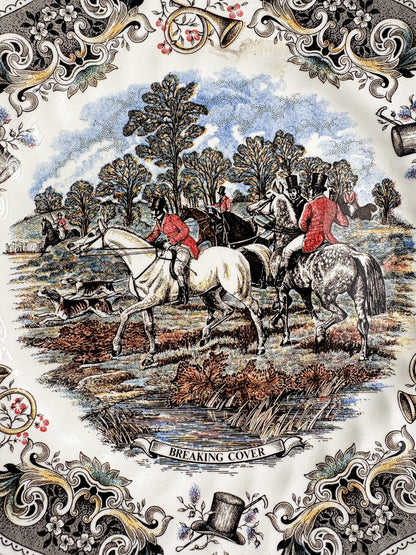 Close-up of the Breaking Cover transfer on a Churchill plate: hunters and hounds leaving woodland cover, a white horse and a spotted grey in the foreground, and the title banner Breaking Cover at the bottom.