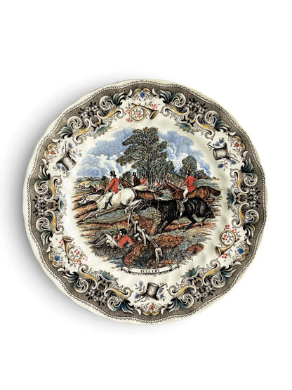 Vintage Churchill Herring’s Hunt dinner plate titled Full Cry, showing a fox-hunting scene with riders in red coats jumping a fence, a fallen huntsman in the foreground, and an ornate grey border of horns, top hats and flowers. Scalloped rim. Photographed from above on a white background.