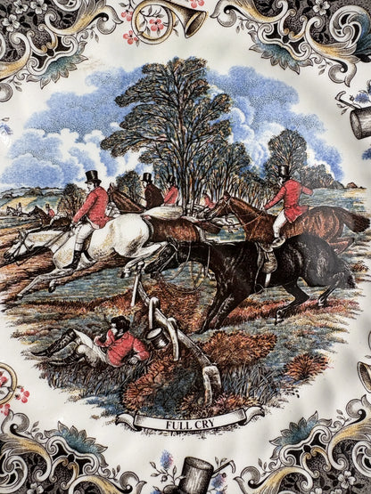 Close-up of the Full Cry transfer on a Churchill plate: hunters on a white horse, a brown horse and a black horse leaping a wooden fence, a rider lying on the ground in a red coat, trees and blue sky behind, with the title banner Full Cry at the bottom.