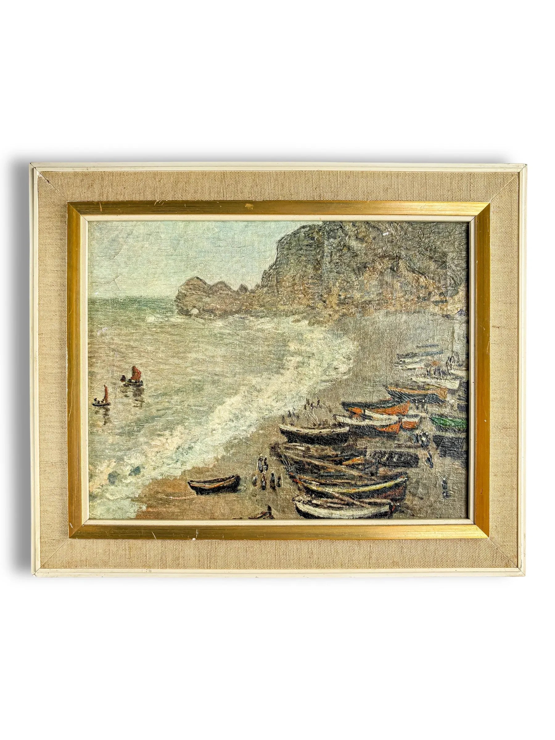 Framed vintage painting of a coastal scene with boats on sandy shore and cliffs in the background