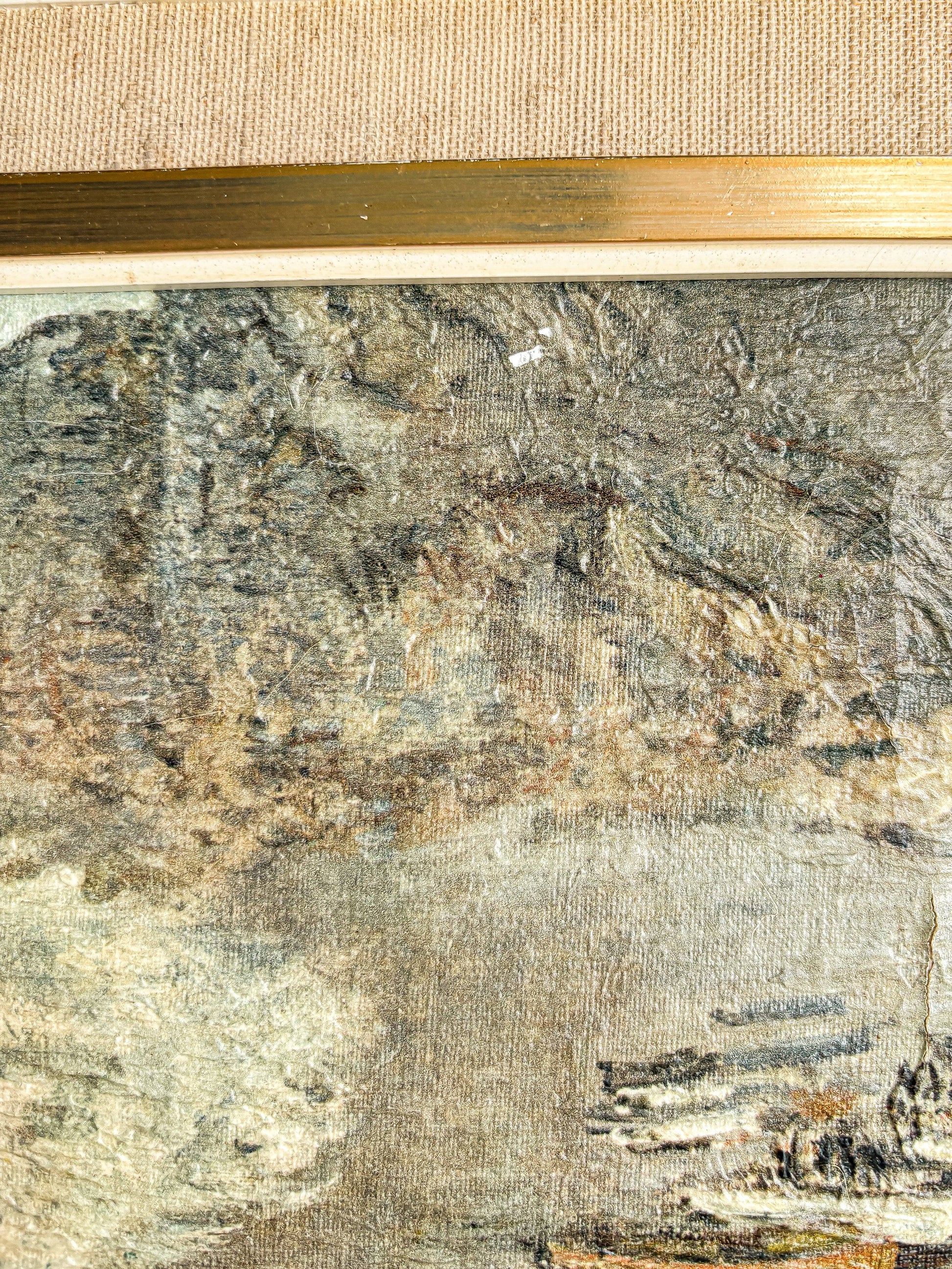 close-up of textured aged canvas painting with muted landscape and gold frame edge
