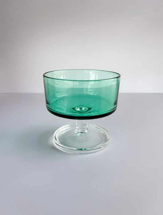Vintage green glass dessert bowl with clear pedestal base on white background