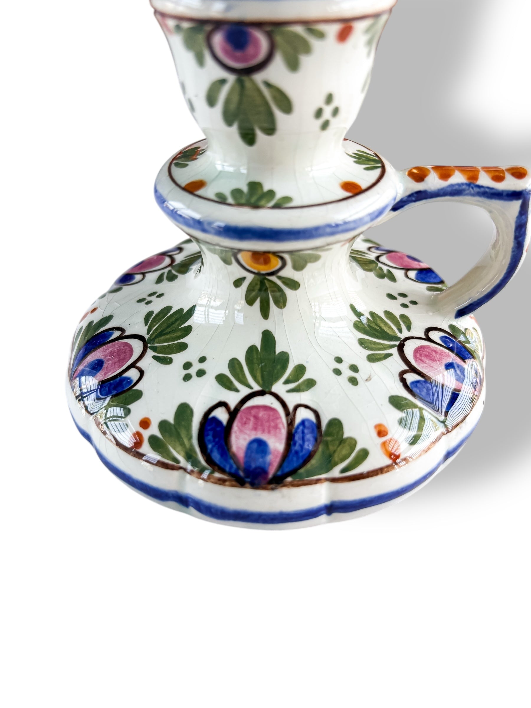 close-up of vintage ceramic candlestick holder with colorful floral patterns and blue trim