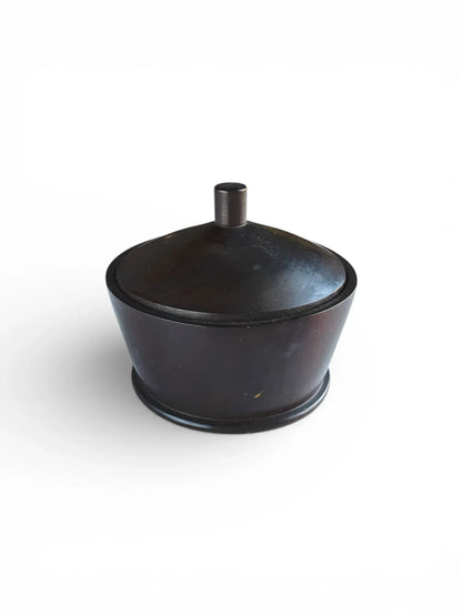 Angled view of a minimalist vintage ebonised wood trinket box with a domed lid and cylindrical knob, set against a plain white background.