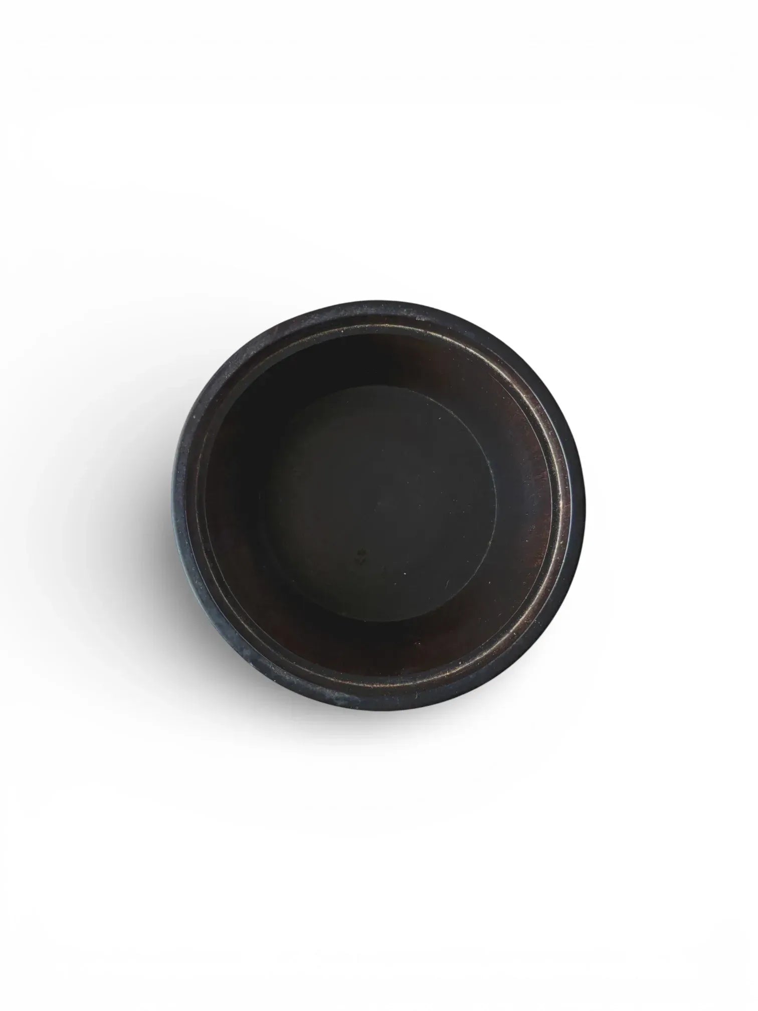 Top-down view looking into an empty vintage black wooden box, showing the dark, smooth turned interior of the bowl.