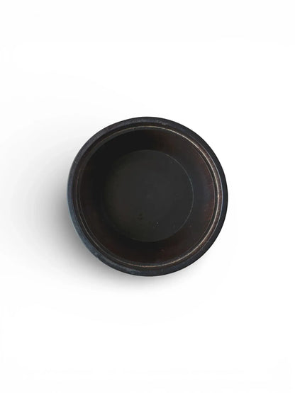 Top-down view looking into an empty vintage black wooden box, showing the dark, smooth turned interior of the bowl.