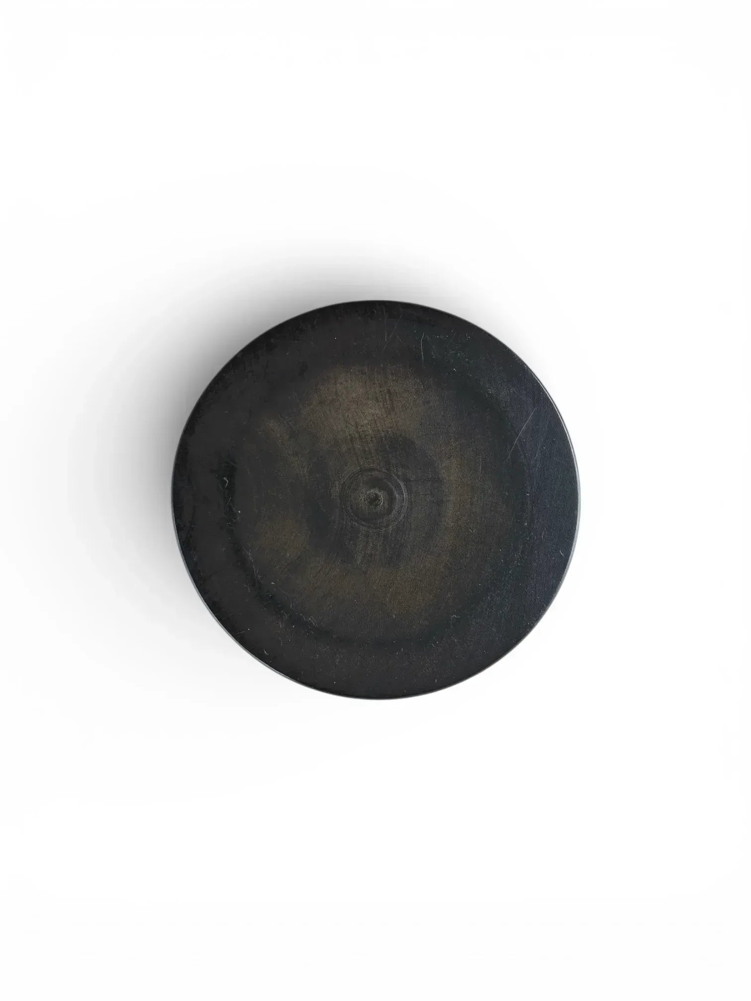 The underside of an ebonised turned wood box, showing circular grain patterns and subtle hints of the lighter natural wood beneath the black finish.