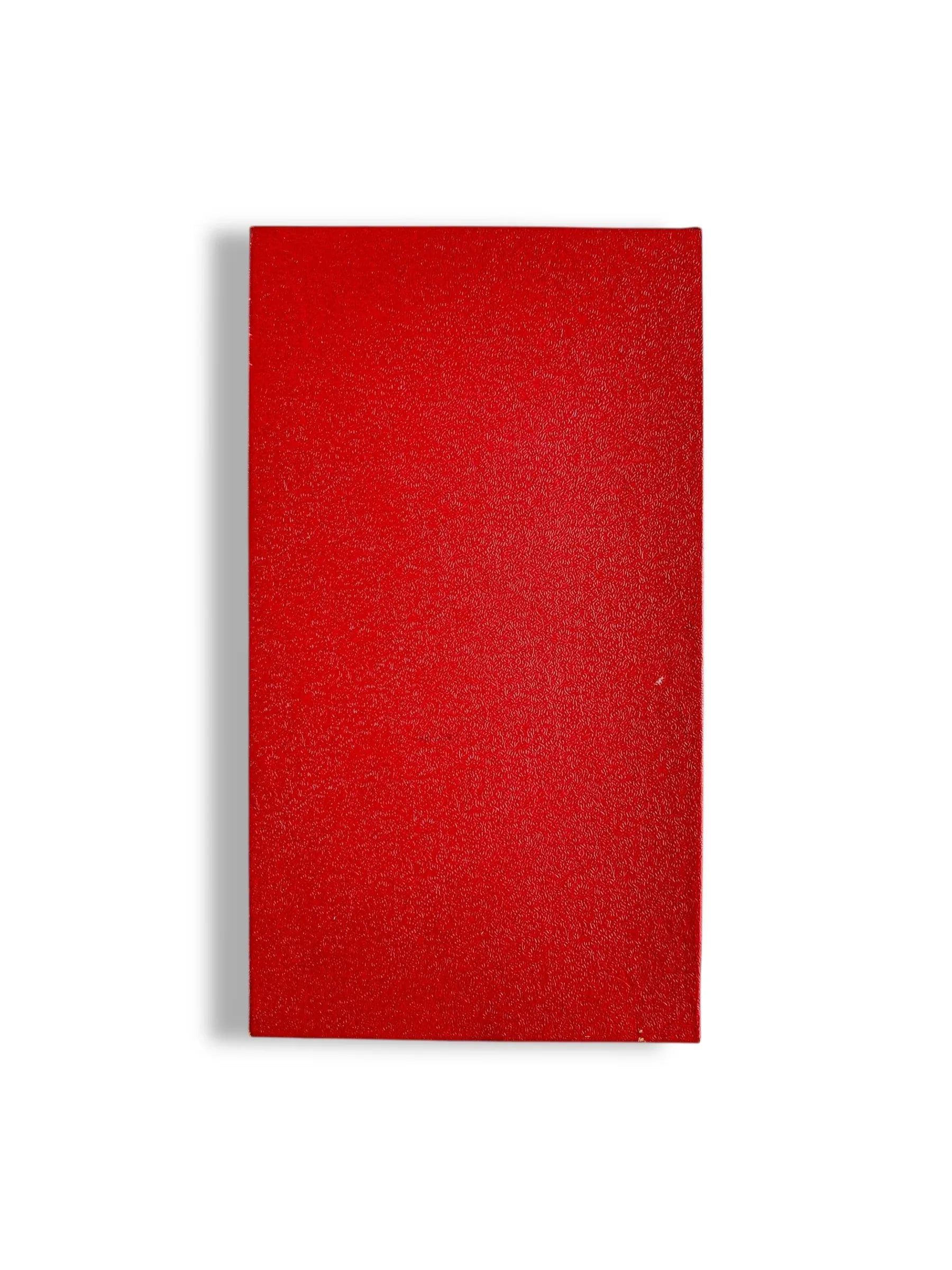 Closed red hardcover book with textured surface on white background