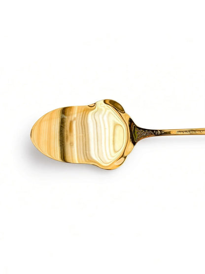 Close-up of the front of the gold plated spoon bowl with bright reflections and floral engraving at the neck