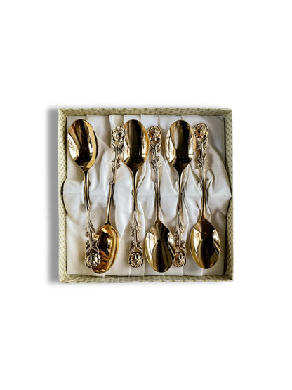 Set of six gold-tone decorative spoons with rose-patterned handles displayed in a lined box