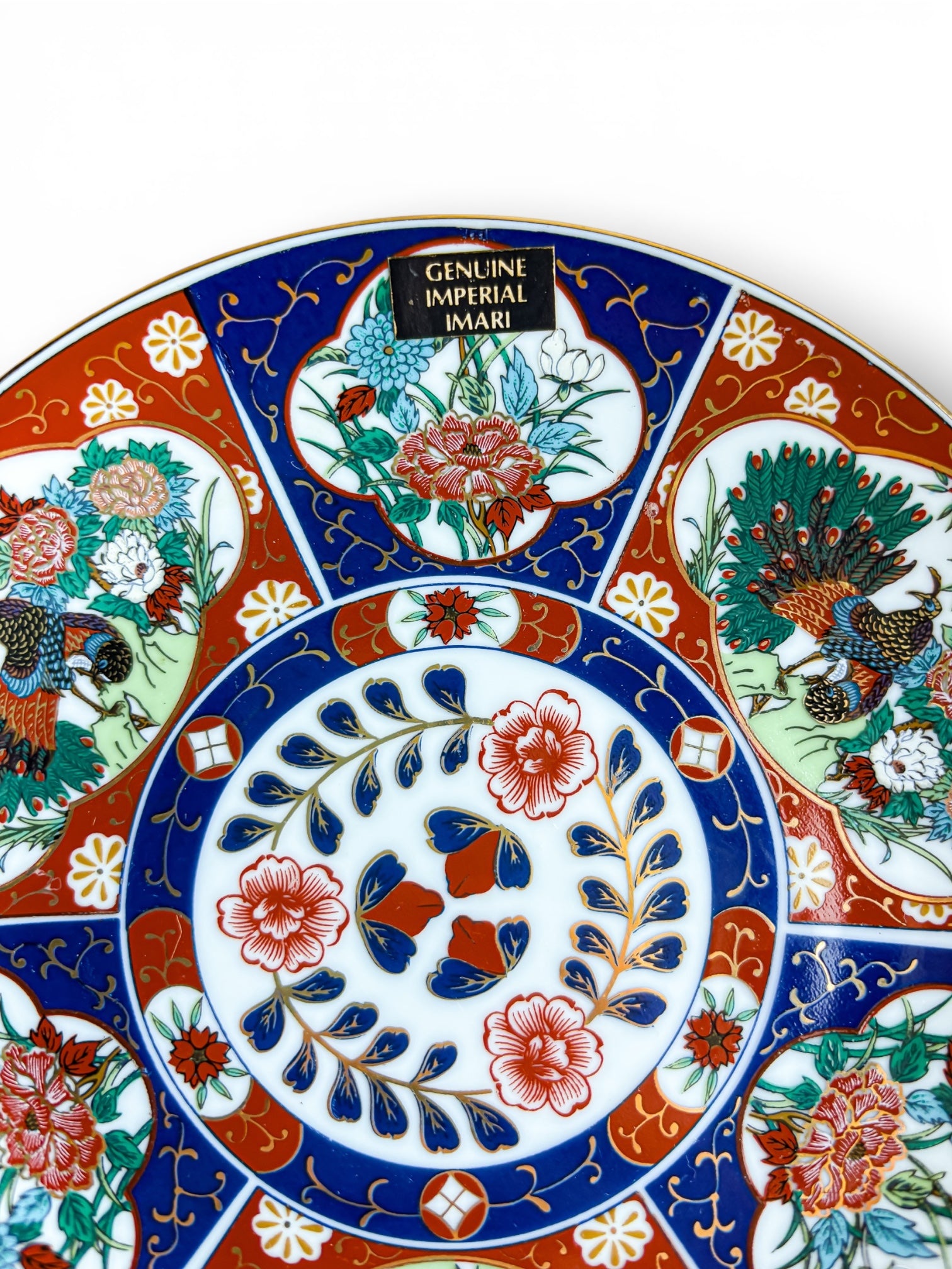Close-up of a genuine imperial Imari porcelain plate with vibrant floral and peacock patterns in red, blue, and green