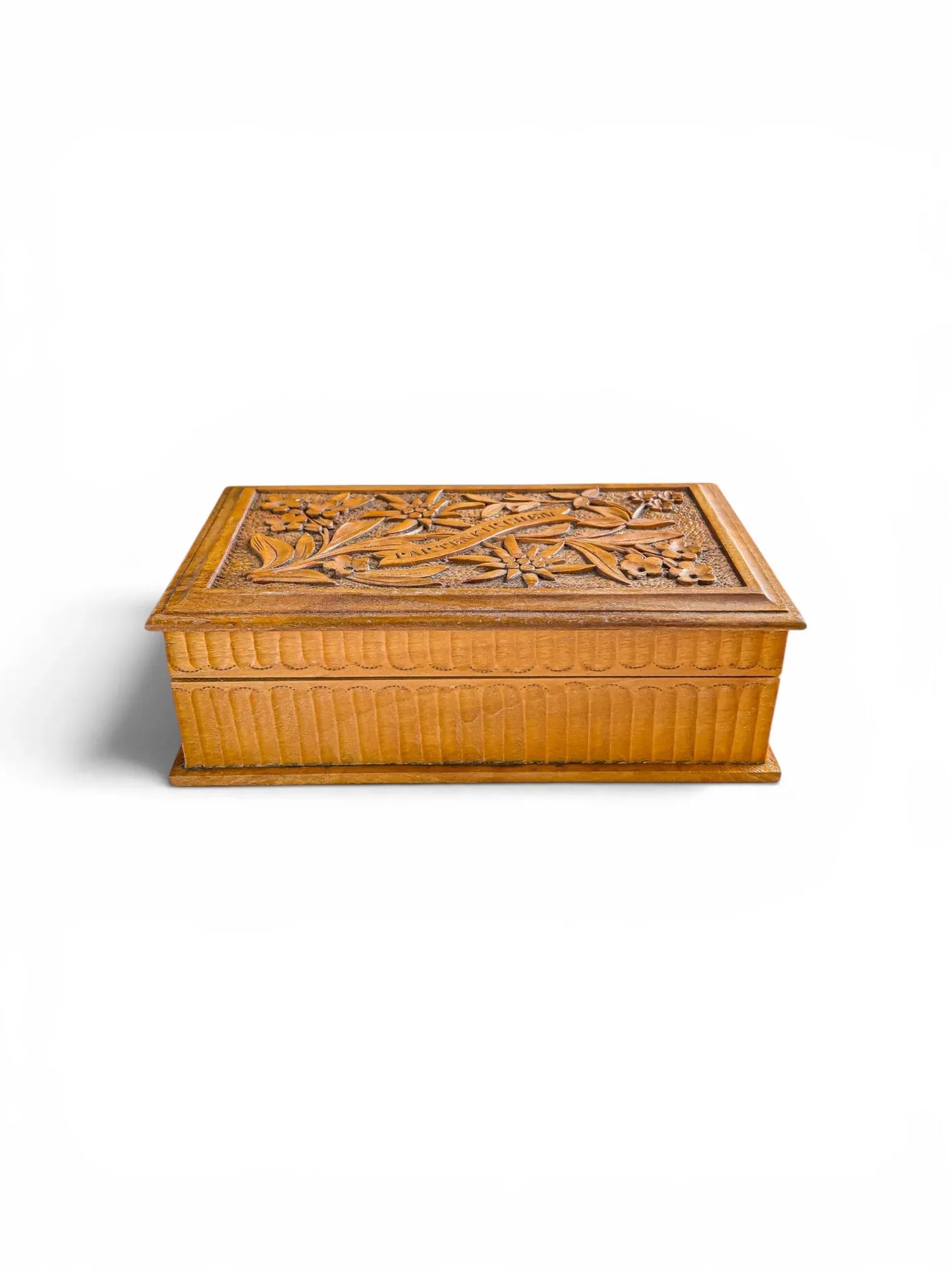 Three-quarter view of a vintage hand-carved lindenwood trinket box with a high-relief floral lid and fluted vertical sides, featuring a warm honey-toned wood patina against a white background.
