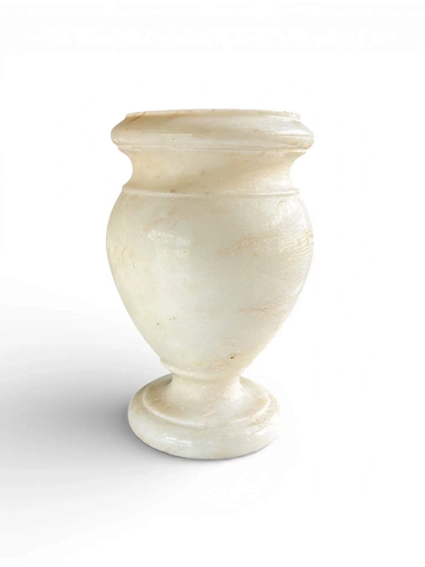 Angled view of a hand-carved neoclassical stone vase highlighting the smooth trophy silhouette and polished pedestal base.