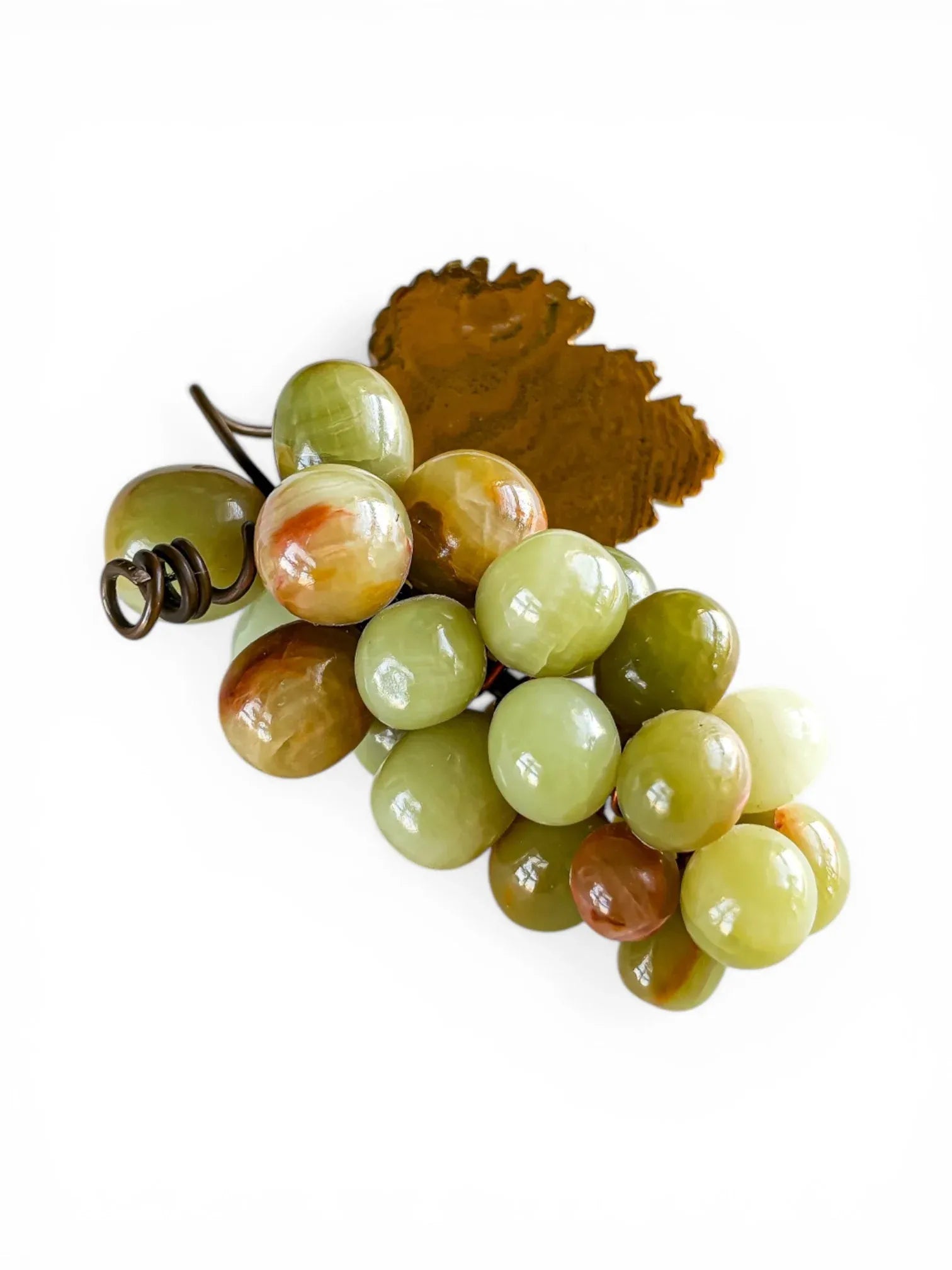 Overhead view of a mid-century decorative grape cluster made from polished banded onyx. The cluster features varied tones of green and amber, secured with a copper-toned wire vine and a stamped metal leaf.