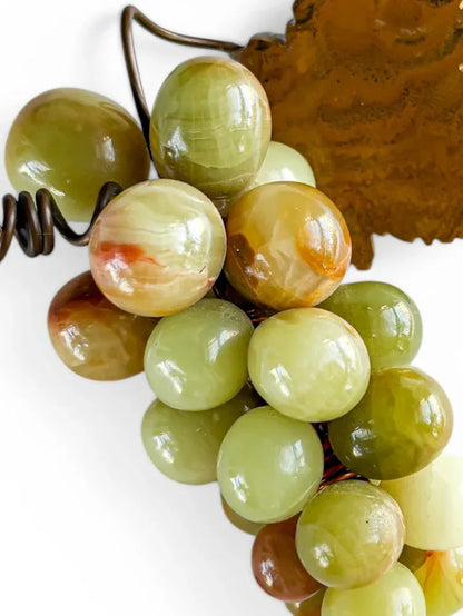Close-up detail of polished onyx grapes showing the intricate natural mineral veining and iron-red inclusions. The high-gloss finish highlights the translucent quality of the genuine banded calcite.