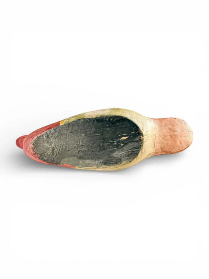 Bottom view of a hand-painted vintage ceramic shoe figurine on white background
