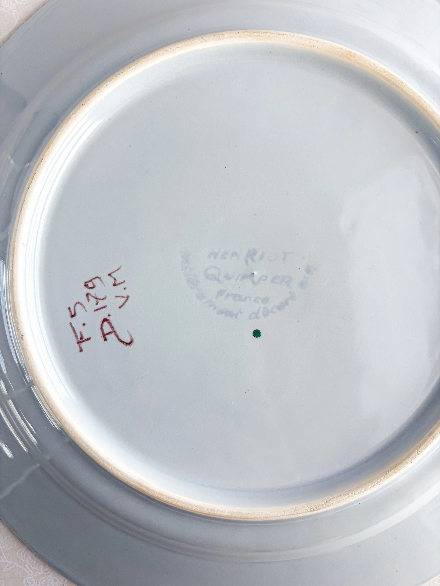 Underside of vintage porcelain plate with Quimper France hallmark and handwritten marks