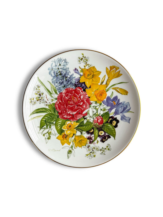 Porcelain plate with colorful floral design featuring red rose, yellow daffodils, purple and white flowers, and green leaves