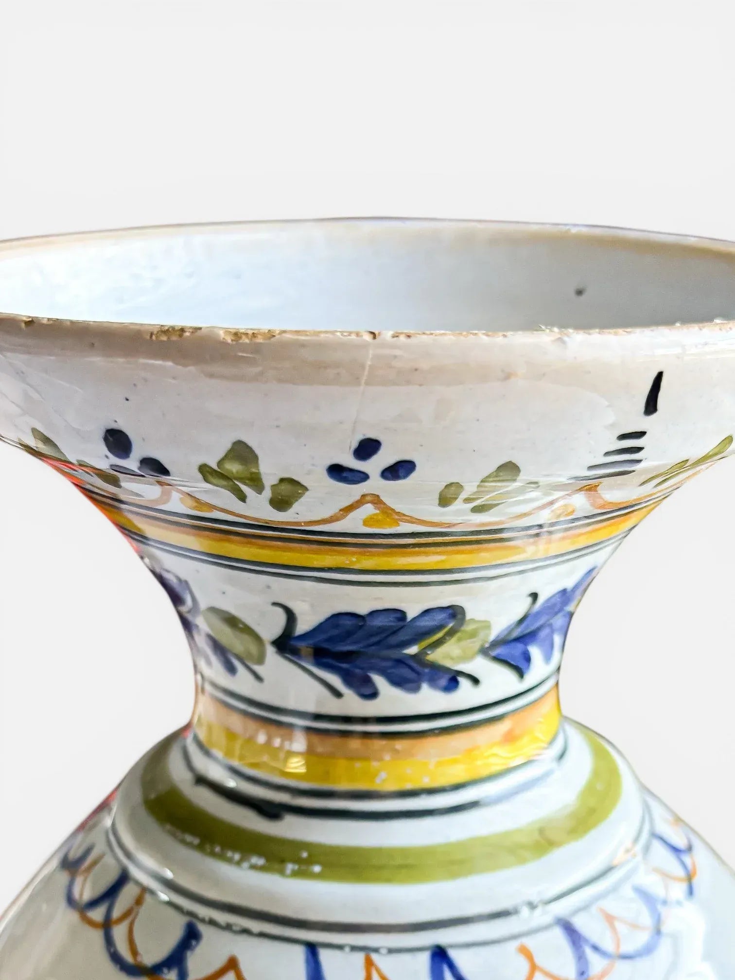 Close-up of the flared rim and neck of a mid-century Italian Majolica vase showing fine hand-painted scrolls and leaf motifs.