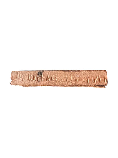 Rectangular rusty metal strip with worn embossed text on a white background