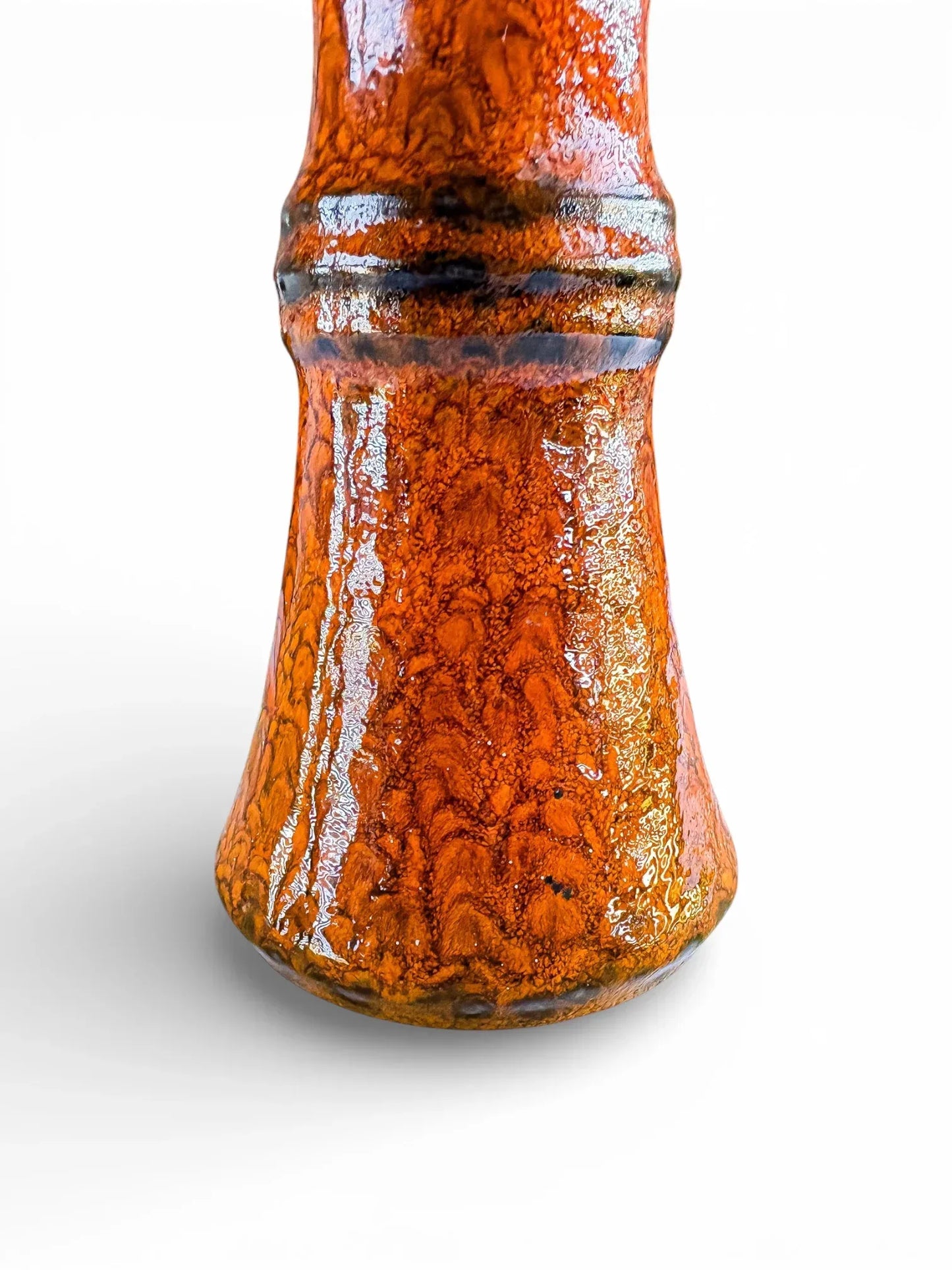 Close-up of orange fat lava glaze with volcanic texture and dark brown banding on Jasba Keramik vase