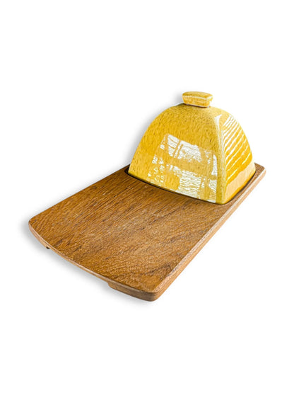 Wooden serving board with a glossy yellow ceramic butter dish cover