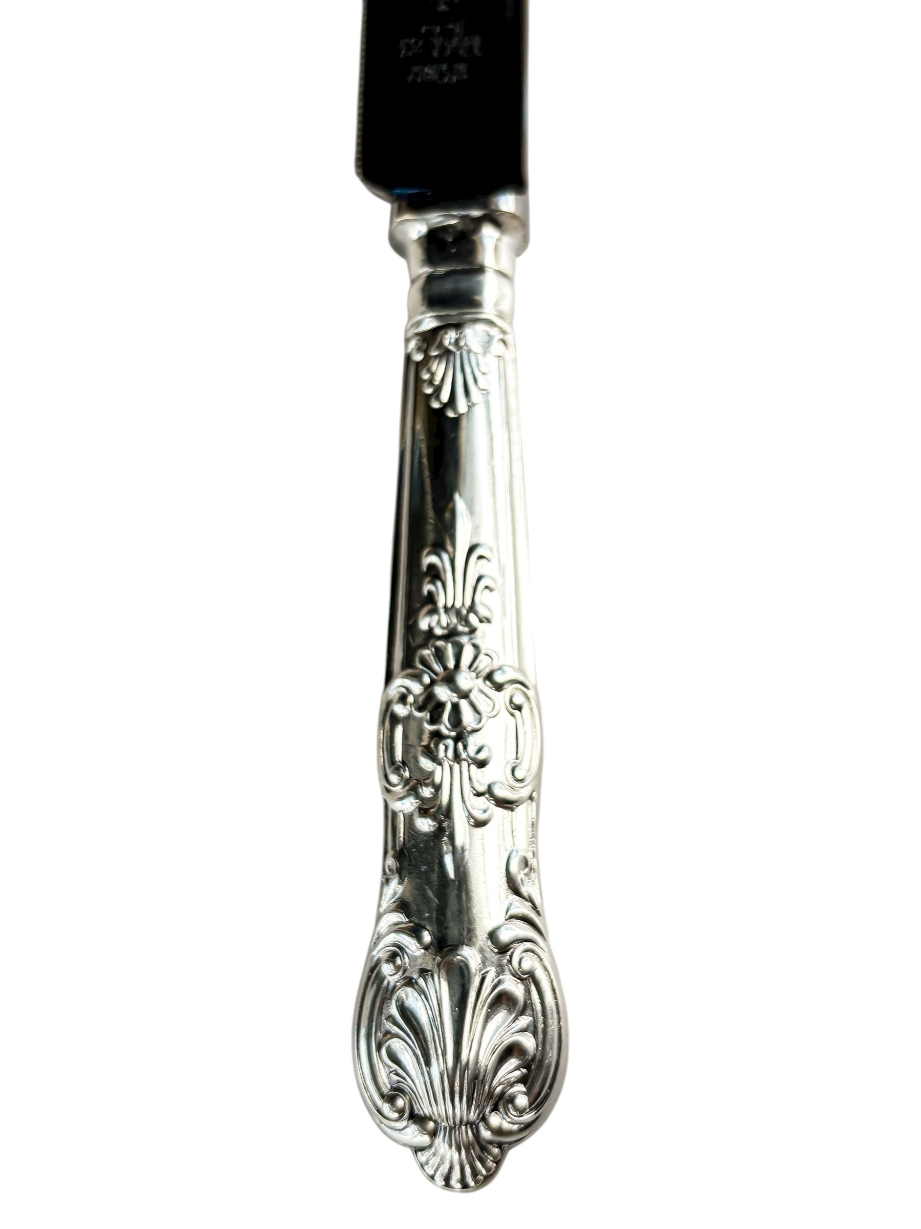 Ornate silverplated cake knife handle with floral and shell pattern on white background