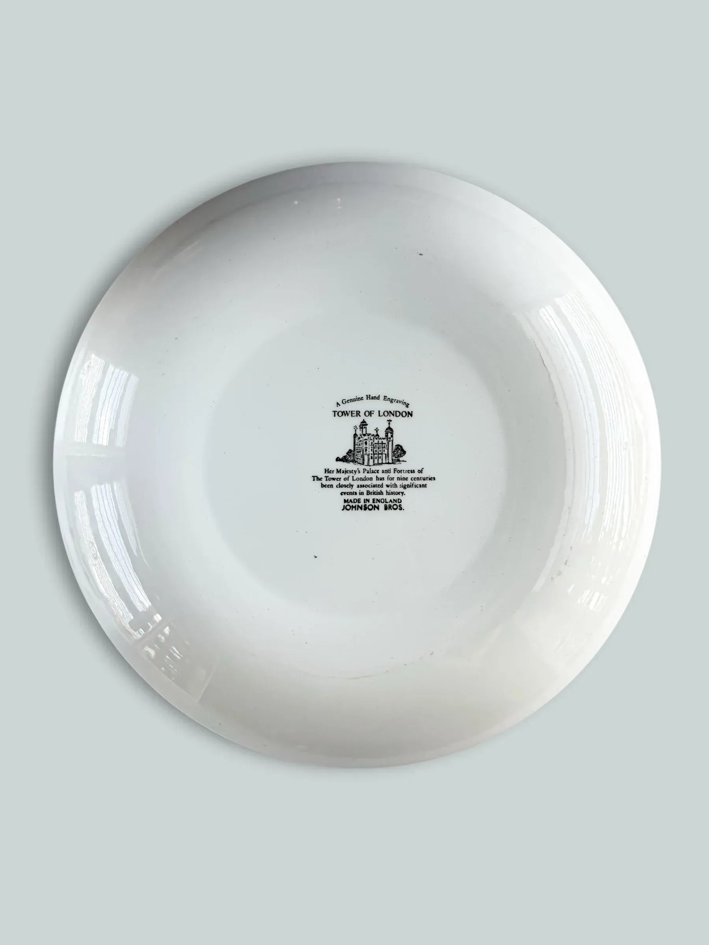 The backstamp of a Johnson Bros England ironstone plate with a historical inscription about the Tower of London and "Genuine Hand Engraving" mark.