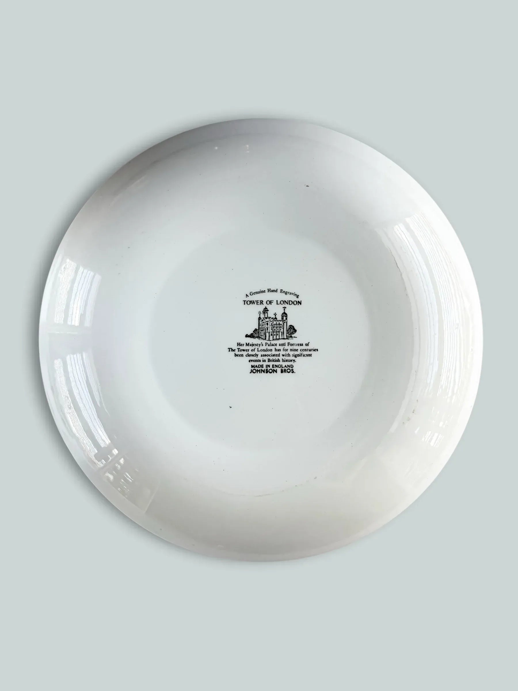 The backstamp of a Johnson Bros England ironstone plate with a historical inscription about the Tower of London and "Genuine Hand Engraving" mark.